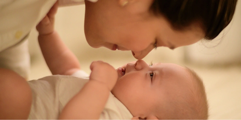 En mor lener seg over en liten baby med nesetipp mot nesetipp